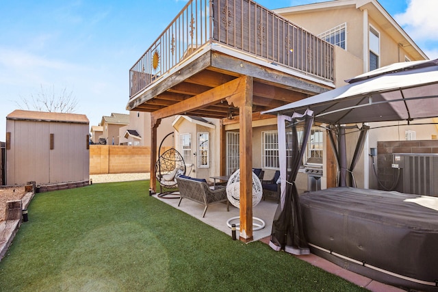 back of house featuring a patio, a gazebo, a shed, a hot tub, and a lawn