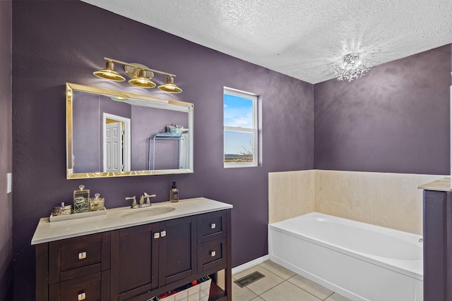 full bathroom with tile patterned floors, a bath, vanity, baseboards, and a textured ceiling