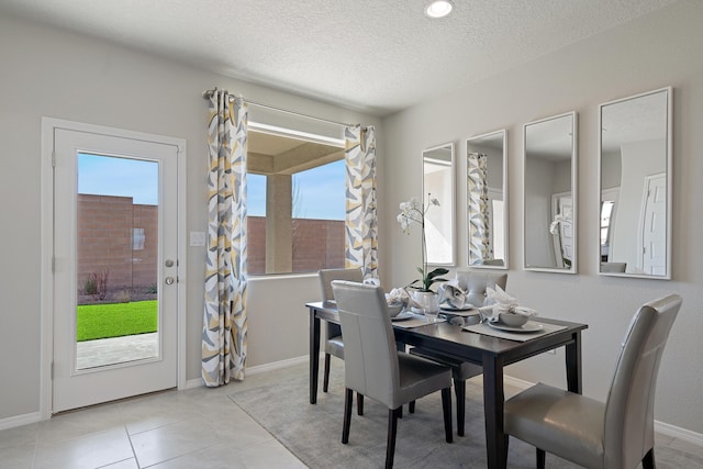 dining space with light tile patterned flooring, a textured ceiling, baseboards, and recessed lighting