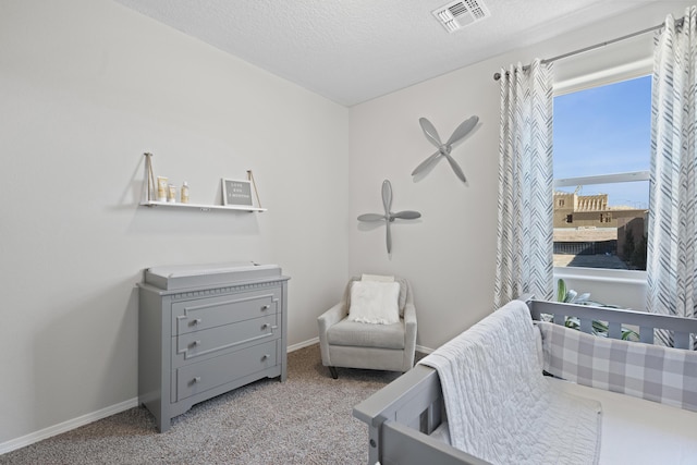 bedroom featuring baseboards, a textured ceiling, visible vents, and carpet