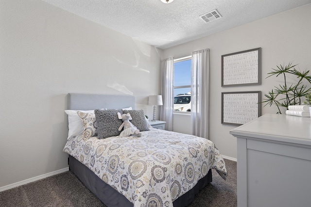 bedroom featuring a textured ceiling, dark carpet, visible vents, and baseboards