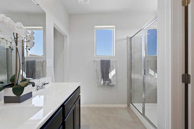 bathroom featuring a tile shower, tile patterned flooring, a sink, and double vanity