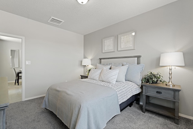 carpeted bedroom with a textured ceiling, visible vents, and baseboards