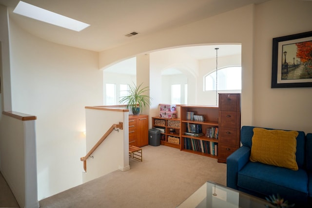 living area featuring an upstairs landing, visible vents, a wealth of natural light, and light carpet