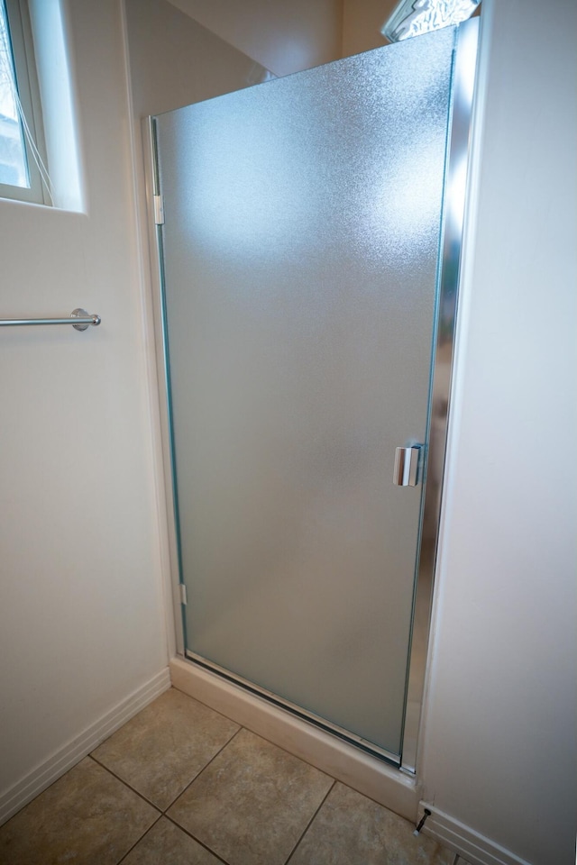 full bathroom featuring tile patterned floors, a shower stall, and baseboards