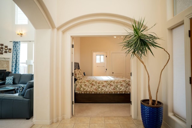 bedroom with light tile patterned floors, arched walkways, and light carpet