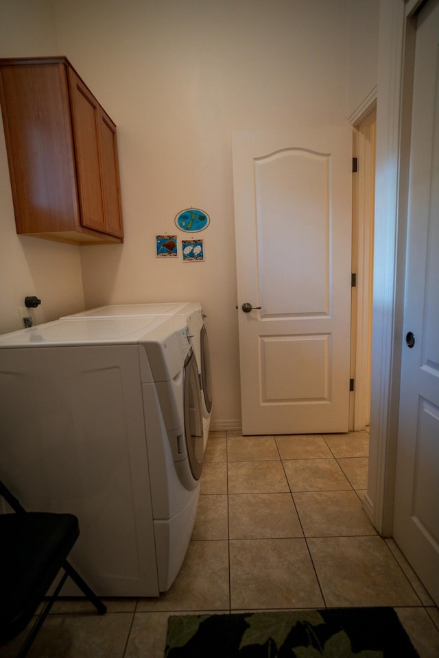 laundry area featuring light tile patterned flooring, washer and clothes dryer, cabinet space, and baseboards