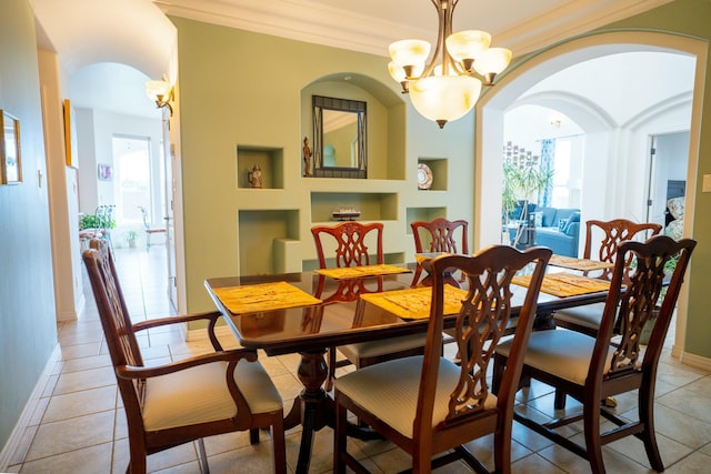 dining area with crown molding, arched walkways, an inviting chandelier, light tile patterned flooring, and built in features