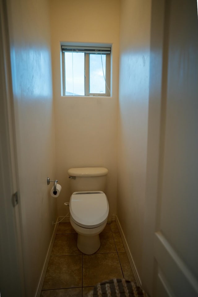 bathroom featuring toilet, tile patterned flooring, and baseboards