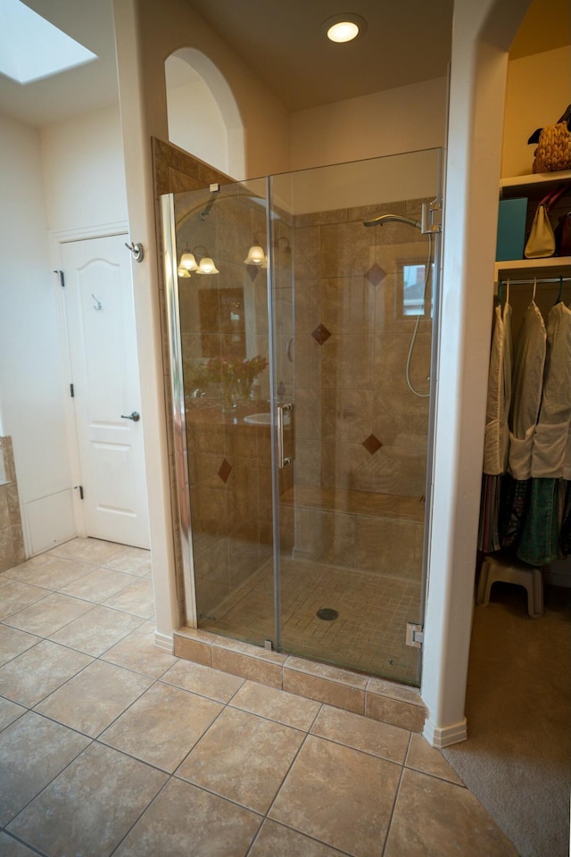 bathroom featuring tile patterned floors, a shower stall, and a skylight