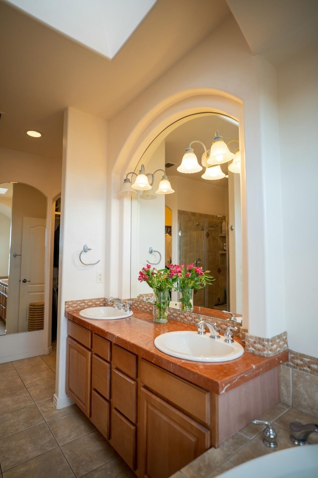 bathroom with a shower stall, tile patterned flooring, double vanity, and a sink