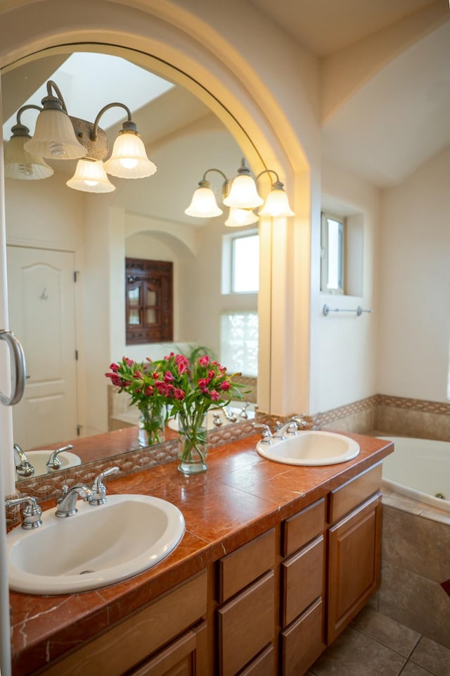 bathroom featuring double vanity, a sink, and tiled tub