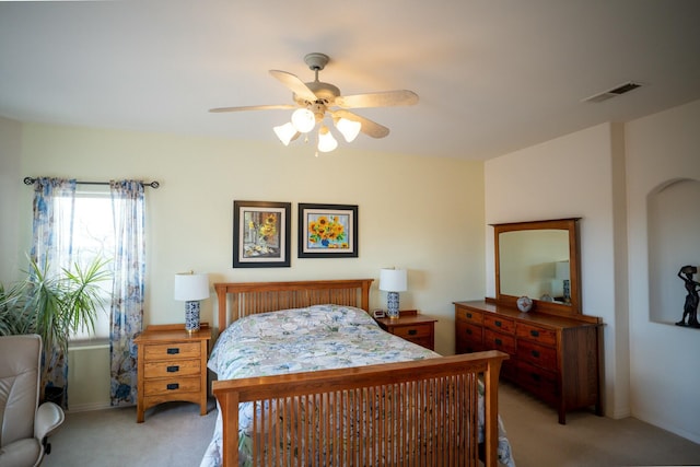 bedroom with visible vents, a ceiling fan, and light carpet