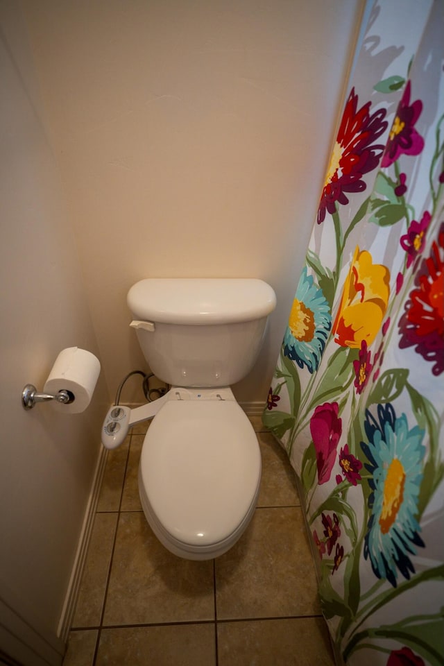 bathroom featuring toilet, tile patterned flooring, a shower with shower curtain, and baseboards