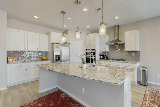 kitchen with stainless steel appliances, tasteful backsplash, visible vents, wall chimney range hood, and white cabinets