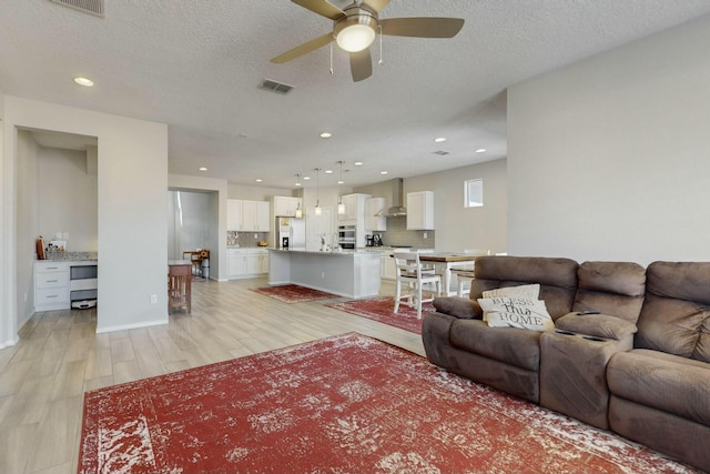 living room with light wood finished floors, a ceiling fan, visible vents, and recessed lighting