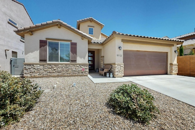 mediterranean / spanish-style home with driveway, stone siding, a tiled roof, an attached garage, and stucco siding