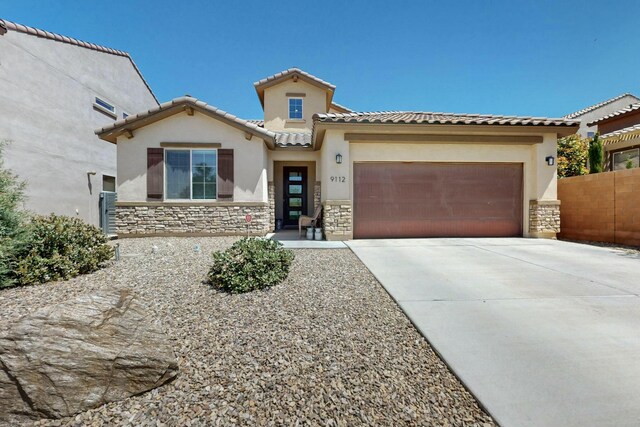 9112 Lansdowne Pl NE, Albuquerque, NM 87113 - mediterranean / spanish-style home with stone siding, a garage, driveway, stucco siding, and a tile roof