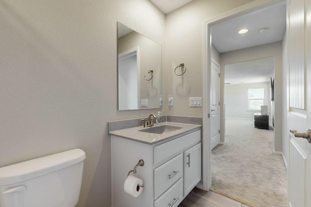 bathroom featuring baseboards, toilet, and vanity