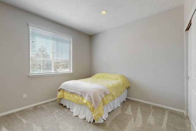 carpeted bedroom featuring baseboards, a textured ceiling, and a closet