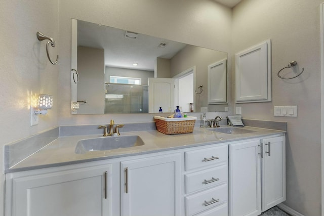 bathroom with a stall shower, double vanity, and a sink