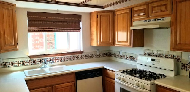 kitchen featuring white appliances, decorative backsplash, under cabinet range hood, light countertops, and a sink