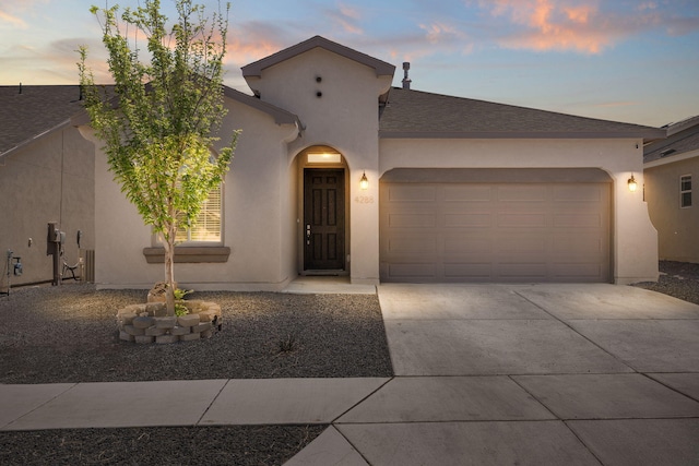 mediterranean / spanish house featuring driveway, roof with shingles, stucco siding, and a garage