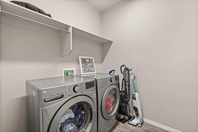 laundry area with wood finished floors, washer and dryer, laundry area, and baseboards
