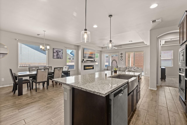 kitchen with an island with sink, stainless steel appliances, a sink, visible vents, and open floor plan