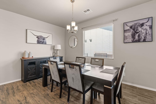 dining area with baseboards, visible vents, wood finished floors, and an inviting chandelier