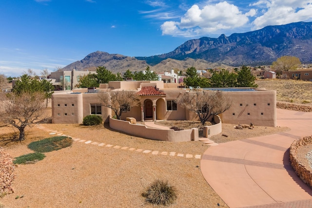 pueblo revival-style home featuring a mountain view, stucco siding, and a tiled roof