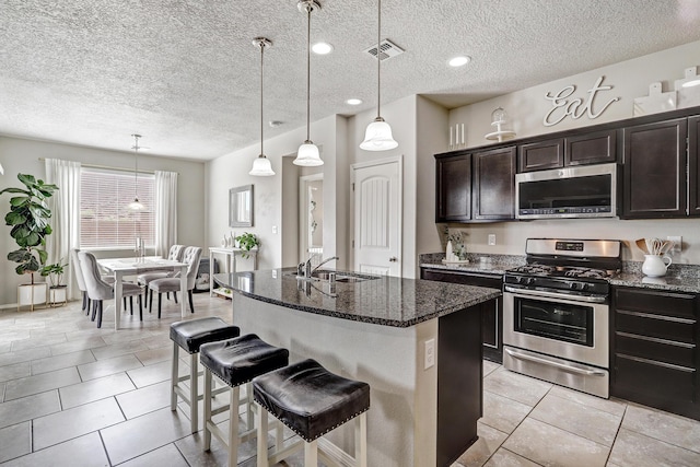 6952 Napoleon Rd NE, Rio Rancho, NM 87144 - kitchen with a textured ceiling, appliances with stainless steel finishes, a sink, and dark stone countertops