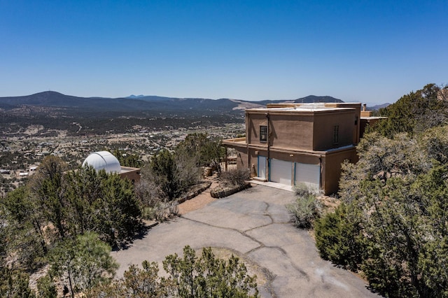 view of property exterior with a mountain view, driveway, a garage, and stucco siding