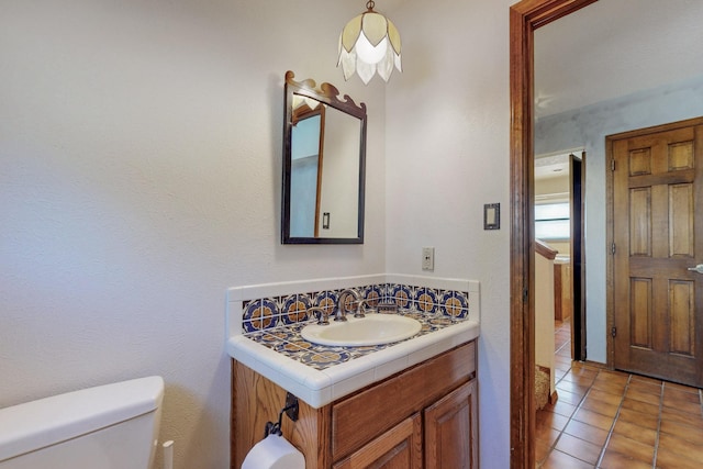 half bathroom featuring toilet, tile patterned flooring, and vanity
