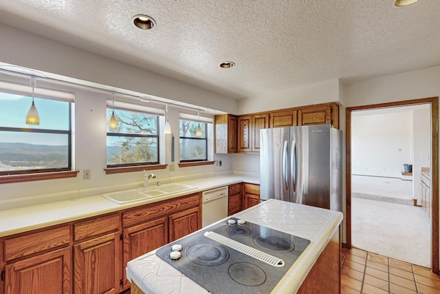 kitchen with black electric stovetop, brown cabinetry, white dishwasher, a sink, and a textured ceiling