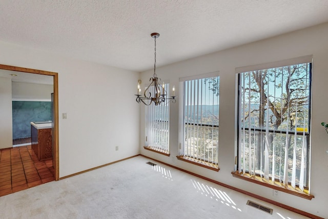 unfurnished dining area with baseboards, visible vents, an inviting chandelier, and carpet floors
