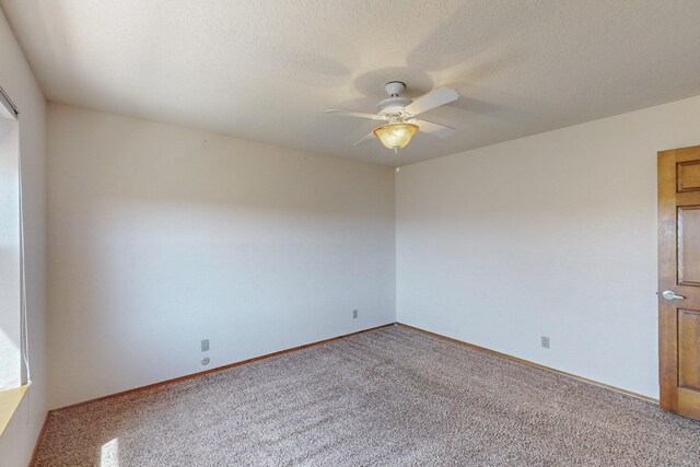 carpeted spare room featuring a ceiling fan and baseboards