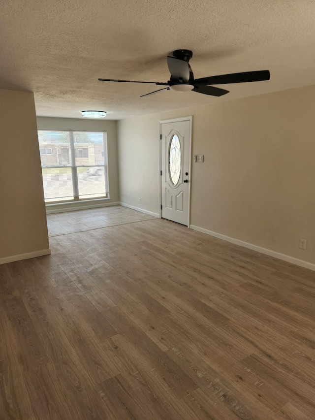 interior space featuring baseboards, a textured ceiling, ceiling fan, and wood finished floors