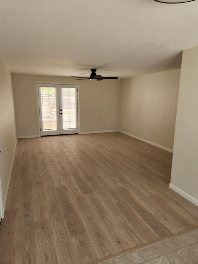 spare room with baseboards, light wood-style flooring, ceiling fan, and french doors