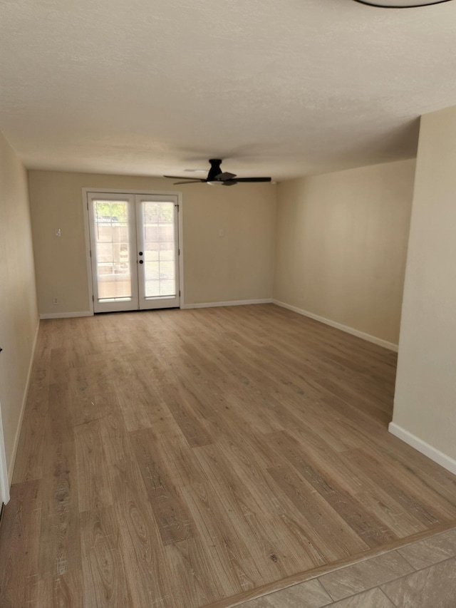 unfurnished room featuring french doors, light wood finished floors, ceiling fan, and baseboards