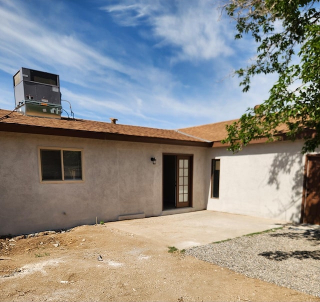 rear view of house with a patio, stucco siding, and central AC