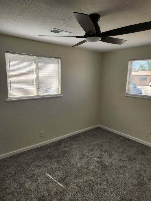 carpeted spare room featuring a ceiling fan and baseboards