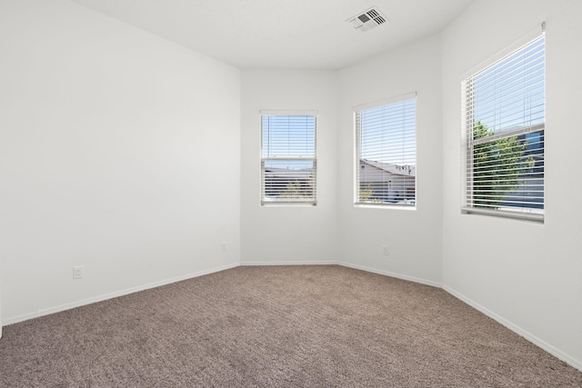 spare room featuring baseboards, visible vents, and carpet