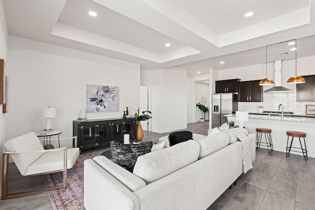 living room featuring a raised ceiling, recessed lighting, and visible vents