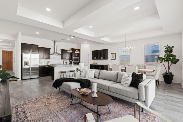 living area with a tray ceiling, recessed lighting, and a chandelier