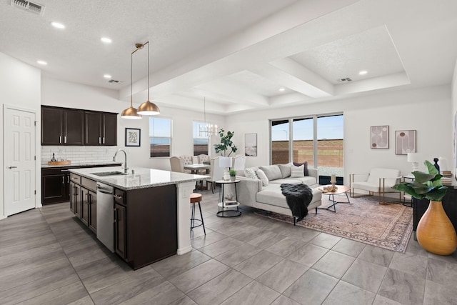 kitchen featuring a sink, dishwasher, a kitchen breakfast bar, visible vents, and a center island with sink