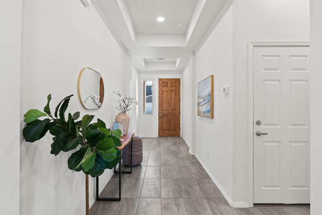 corridor with a raised ceiling, baseboards, and recessed lighting