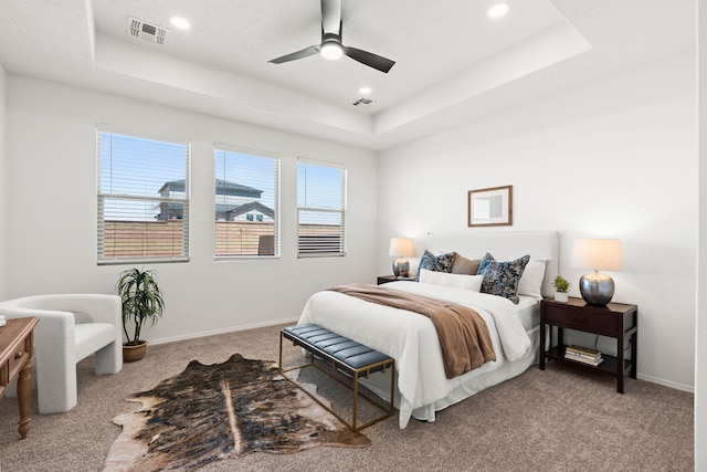 bedroom featuring carpet flooring, a tray ceiling, and visible vents