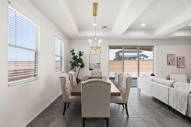 dining room with an inviting chandelier, dark tile patterned floors, a tray ceiling, and visible vents