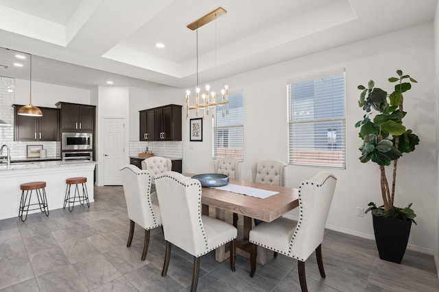 dining area featuring a raised ceiling, baseboards, recessed lighting, and a notable chandelier